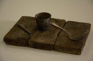 Original cup, knife handle and fork from the crash site of the Hindenburg sitting on original bricks from the floor of Hanger 1, the Hindenburg's home at Lakehurst NAS in the 1930s.
