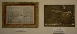 The framed print on the left is an original 1906 print of the USS Maine. The bronze plaque on the right was cast in 1913 from original pieces of metal taken off the USS Maine when she was taken out of the harbor in Havana into deep water and sunk. There were only 1000 castings of which fewer than 50 are known to exist today.