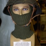 Cold War era East German Army combat steel helmet with camouflage neting and knitted winter pullover.