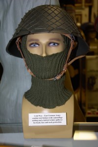 Cold War era East German Army combat steel helmet with camouflage neting and knitted winter pullover.